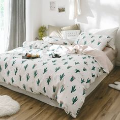 a bed with white sheets and green cactus print on it, next to a window