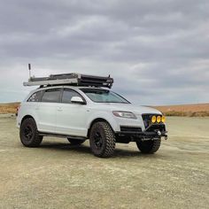 a white suv parked on top of a dirt field