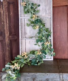 a wooden box with some flowers and greenery on it next to an old door