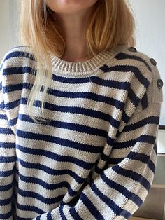 a woman with blonde hair wearing a blue and white striped sweater