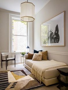 a living room filled with furniture and a painting hanging on the wall next to a window