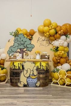 a winnie the pooh themed birthday party with balloons and honeycombs on display