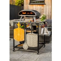 an outdoor bbq grill with various cooking utensils on the table and in front of it