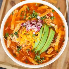 a bowl of chicken tortilla soup with an avocado slice on top