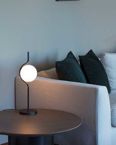 a table lamp sitting on top of a wooden table next to a white couch in a living room