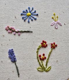 the embroidery is being worked on by someone who has stitched flowers and stems in it