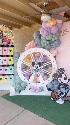 a room decorated with balloons, mickey mouse and minnie mouse on the wall next to a ferris wheel