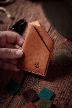 a person holding a wallet on top of a wooden table next to coins and other items