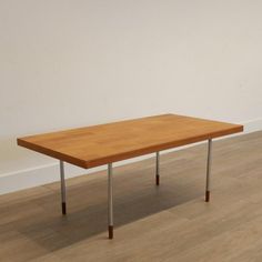 a wooden table sitting on top of a hard wood floor next to a white wall