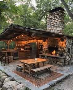 an outdoor kitchen is lit up with string lights and fire pit in the back yard