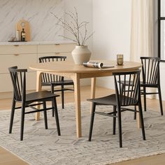 a dining room table with four chairs and a vase