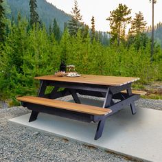 a picnic table sitting on top of a cement slab in the middle of a forest