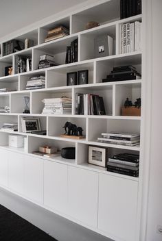 a bookshelf filled with lots of books next to a black and white sculpture