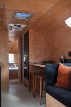 the interior of a small home with wood paneling on the walls and ceiling, along with bar stools