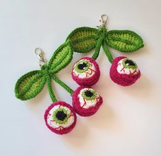 crocheted keychains with eyeballs and leaves attached to them on a white surface