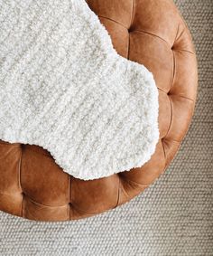 a brown leather chair with a white knitted blanket on it's back cushion