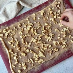 a person is placing chopped apples on top of a doughnut crust in the shape of a rectangle