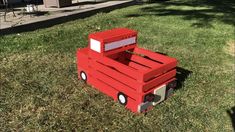 a toy truck made out of pallets sitting in the grass next to a house