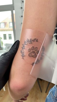 a person with a dog paw tattoo on their left arm and the other hand behind them