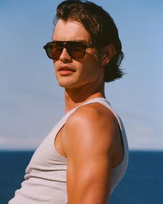 a man wearing sunglasses standing in front of the ocean