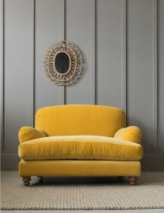 a yellow couch in front of a gray wall with a circular mirror on the wall