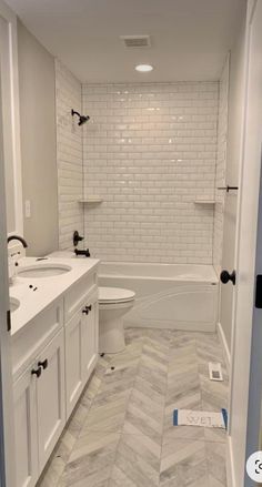 a white bathroom with herringbone tile flooring