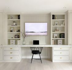 an office with white bookcases, desk and chair