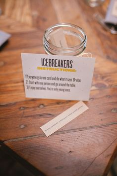 a glass jar sitting on top of a wooden table next to a note with ice breakers written on it