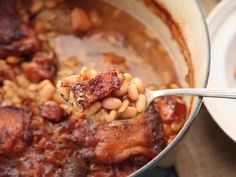 a spoon full of beans and meat in a pot