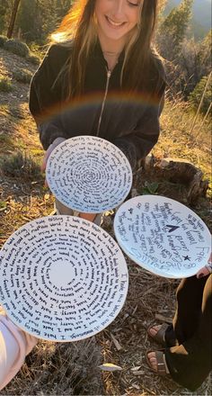 a woman kneeling down next to three plates with writing on them and a rainbow in the background