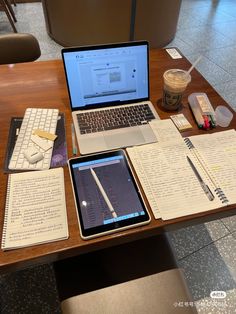 an open laptop computer sitting on top of a wooden desk next to notebooks and papers