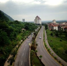 an aerial view of a street with cars driving on it and buildings in the background