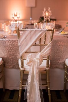 a chair with a bow tied to it sitting in front of a table filled with chairs