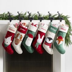 christmas stockings hanging from a mantel decorated with animals and snowman's names