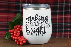 a white wine glass with the words making spirits bright on it next to some red berries