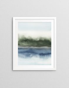 an abstract painting with blue and green watercolors on the paper in a white frame