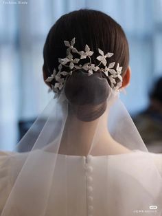 the back of a woman's head wearing a veil and tiara with flowers on it