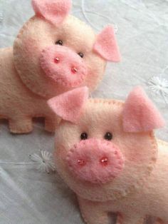 two little pink pigs sitting on top of a white cloth covered table next to each other