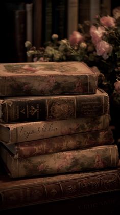 three books are stacked on top of each other in front of flowers and bookshelves