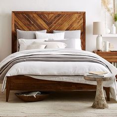 a bedroom with white bedding and wooden headboard