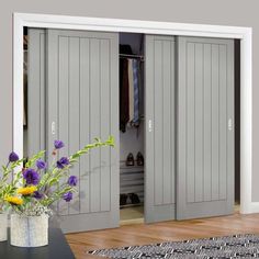 a vase filled with flowers on top of a wooden table next to white closet doors