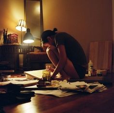 a woman sitting on the floor in front of a mirror looking at papers and pens