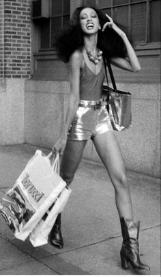 a black and white photo of a woman carrying shopping bags