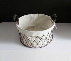 a white basket with black handles sitting on top of a table