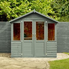 a small gray shed sitting in the middle of a yard