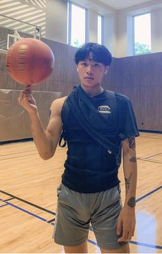 a young man holding a basketball on top of a hard wood floored gym court