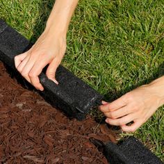 a person is placing their hand on top of a black piece of wood in the ground