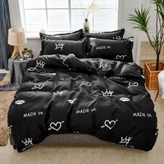 a bed covered in black sheets with white hearts and crowns printed on the comforter