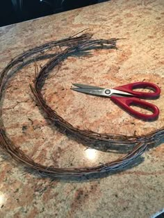 a pair of red scissors sitting on top of a counter next to a wire wrapped around it