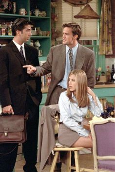 two men and a woman standing in a kitchen talking to each other while the man is holding a briefcase